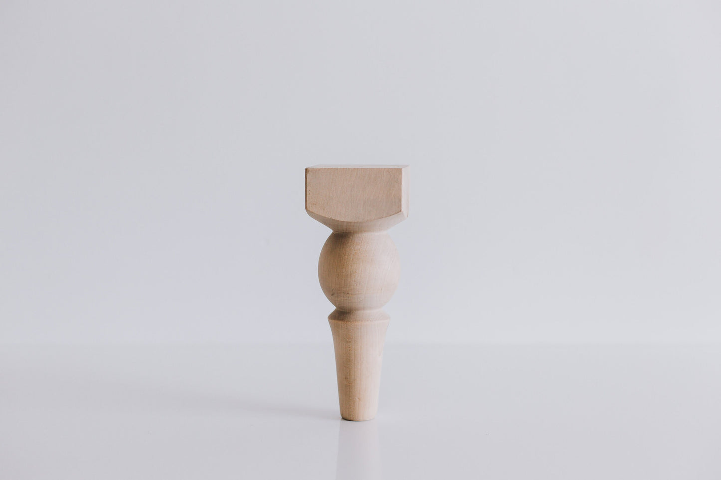 A single wooden furniture leg with a ball design at the top, displayed against a white background.