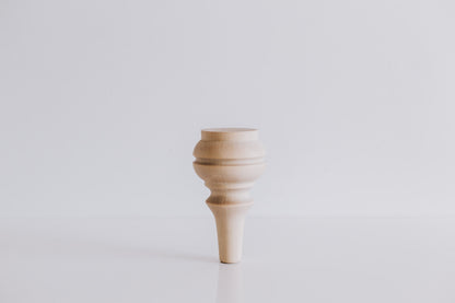 A single handmade wooden furniture leg against a white background, showcasing a natural wood grain and crafted shape.