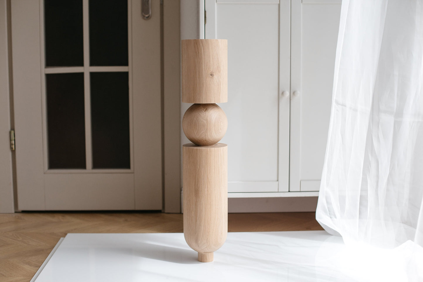 A single wooden furniture leg with a sphere at the top, placed against a white background.