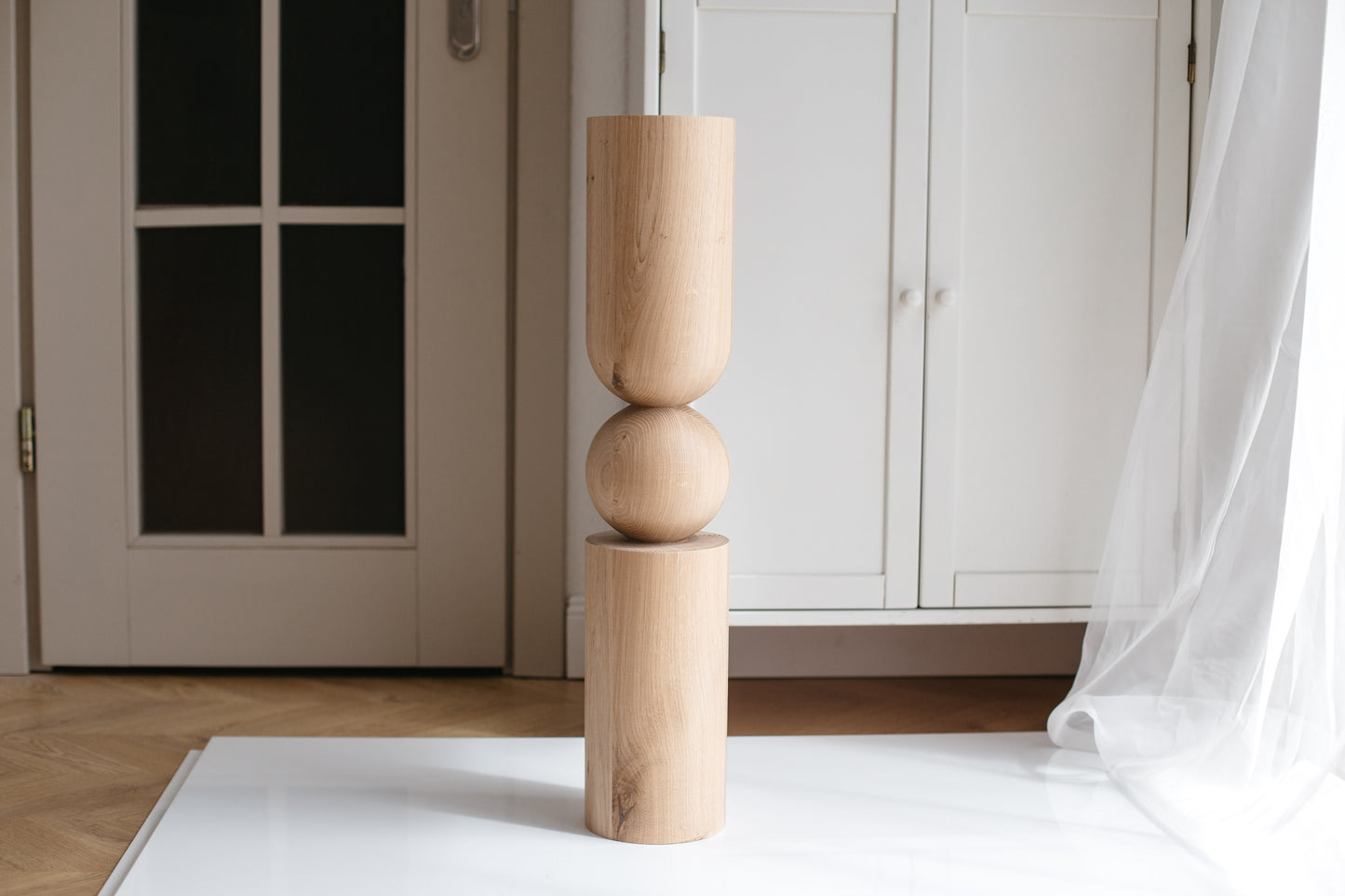 Wooden sculpture on a white rug with a neutral background