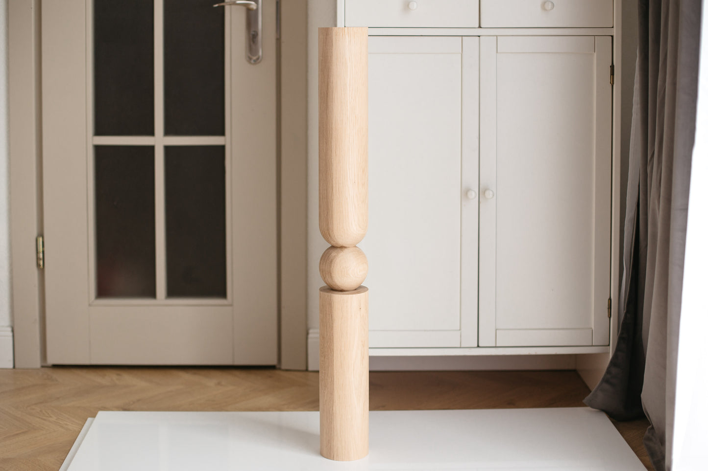 Wooden baluster against a neutral-colored wall with a door and cabinet.