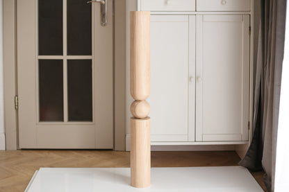 Wooden baluster against a neutral-colored wall with a door and cabinet.