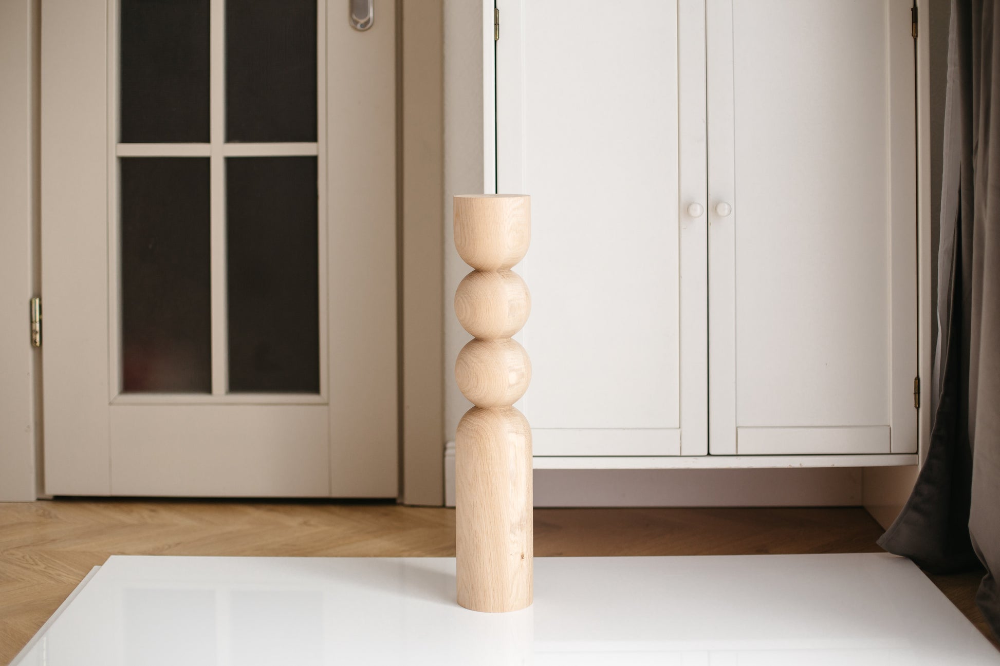 Wooden candle holder on a white surface with a neutral background