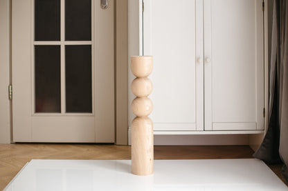 Wooden candle holder on a white surface with a neutral background