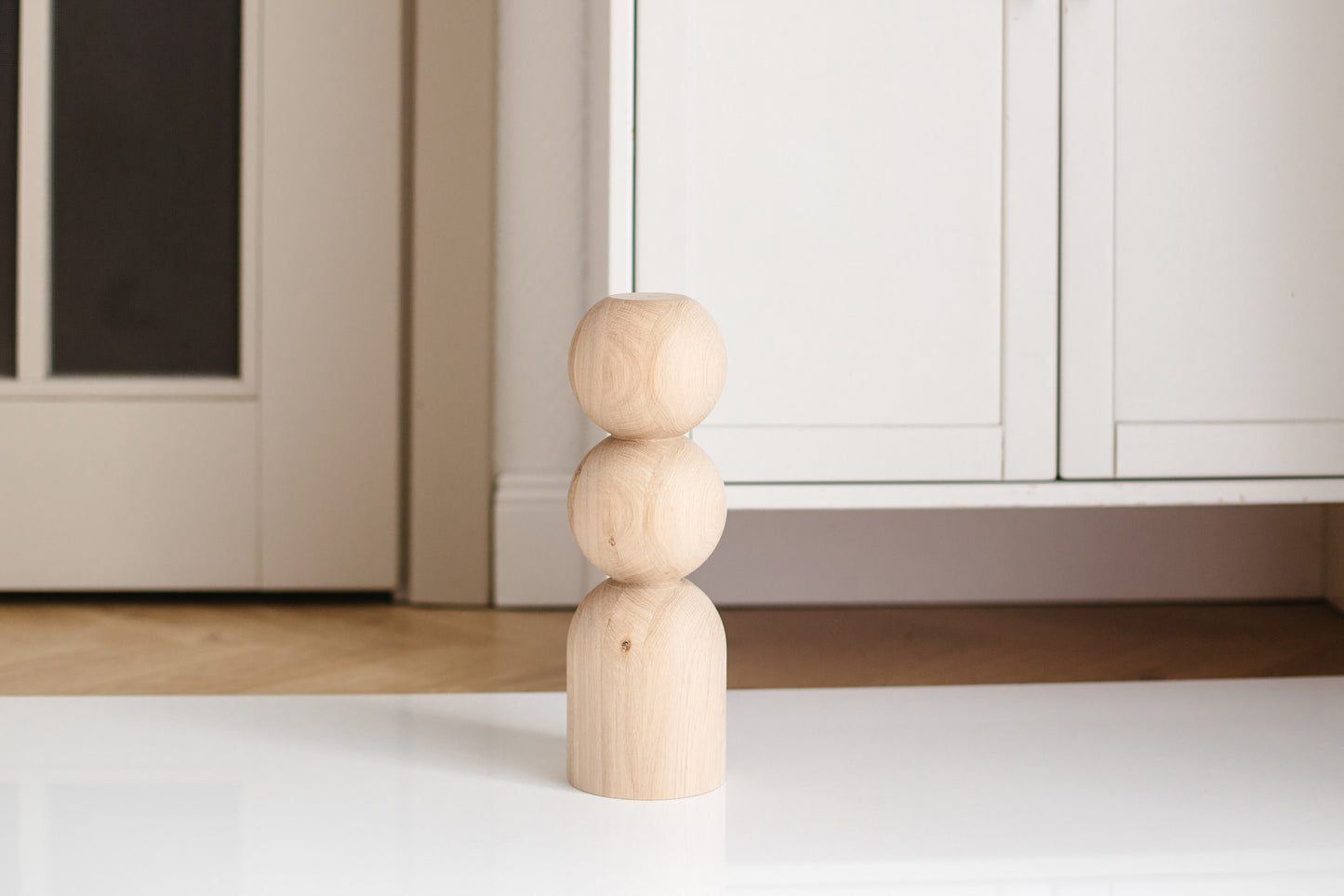 Wooden cylindrical object on a white floor with a neutral-colored wall in the background