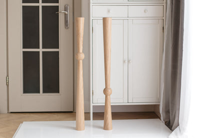 Two wooden balusters on a white rug in a room with a door and cabinets.