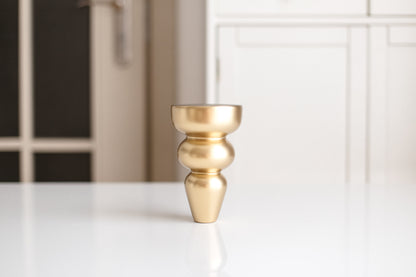 Gold decorative vase on a white surface with a blurred background