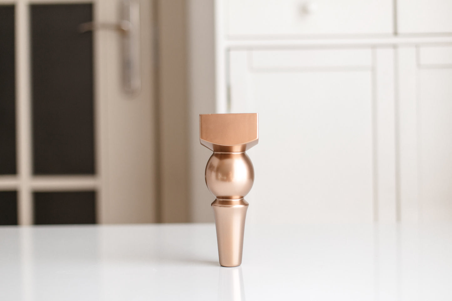 Bronze-colored decorative vase on a white surface with a blurred background