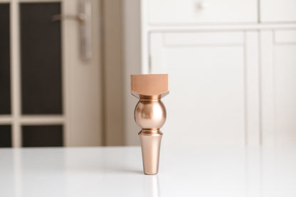 Bronze-colored decorative vase on a white surface with a blurred background