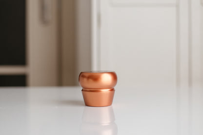 Copper-colored pot on a white surface with a blurred background