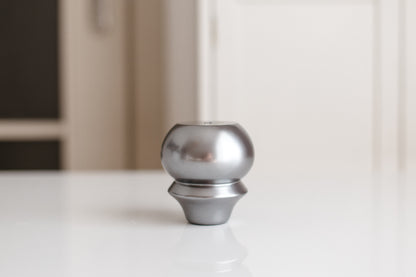 Metallic knob on a white surface with a blurred background
