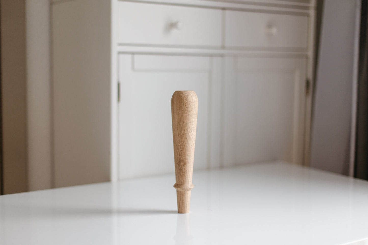 Wooden rolling pin on a white surface with a blurred background