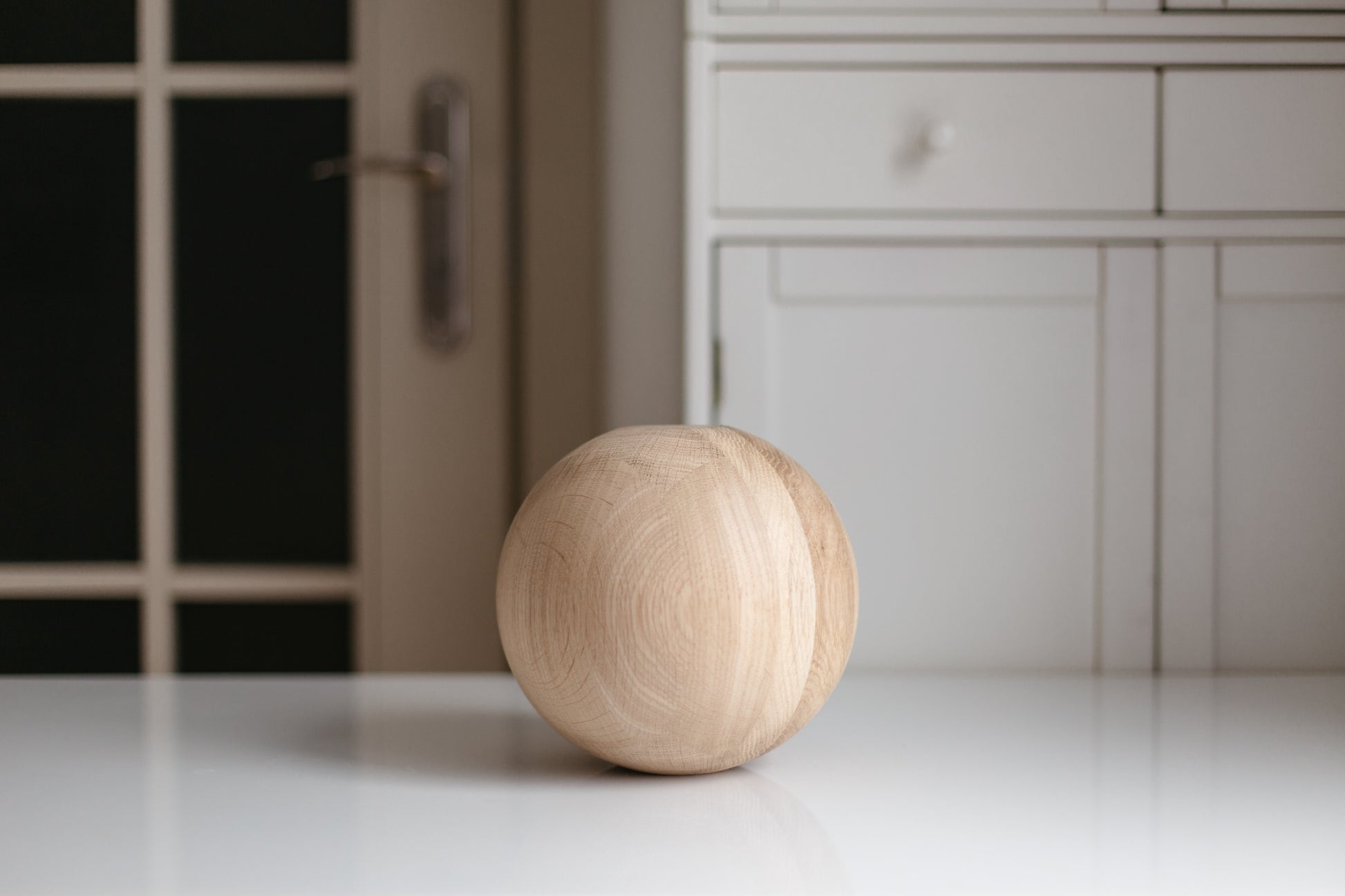 Wooden ball on a white surface with a blurred kitchen background