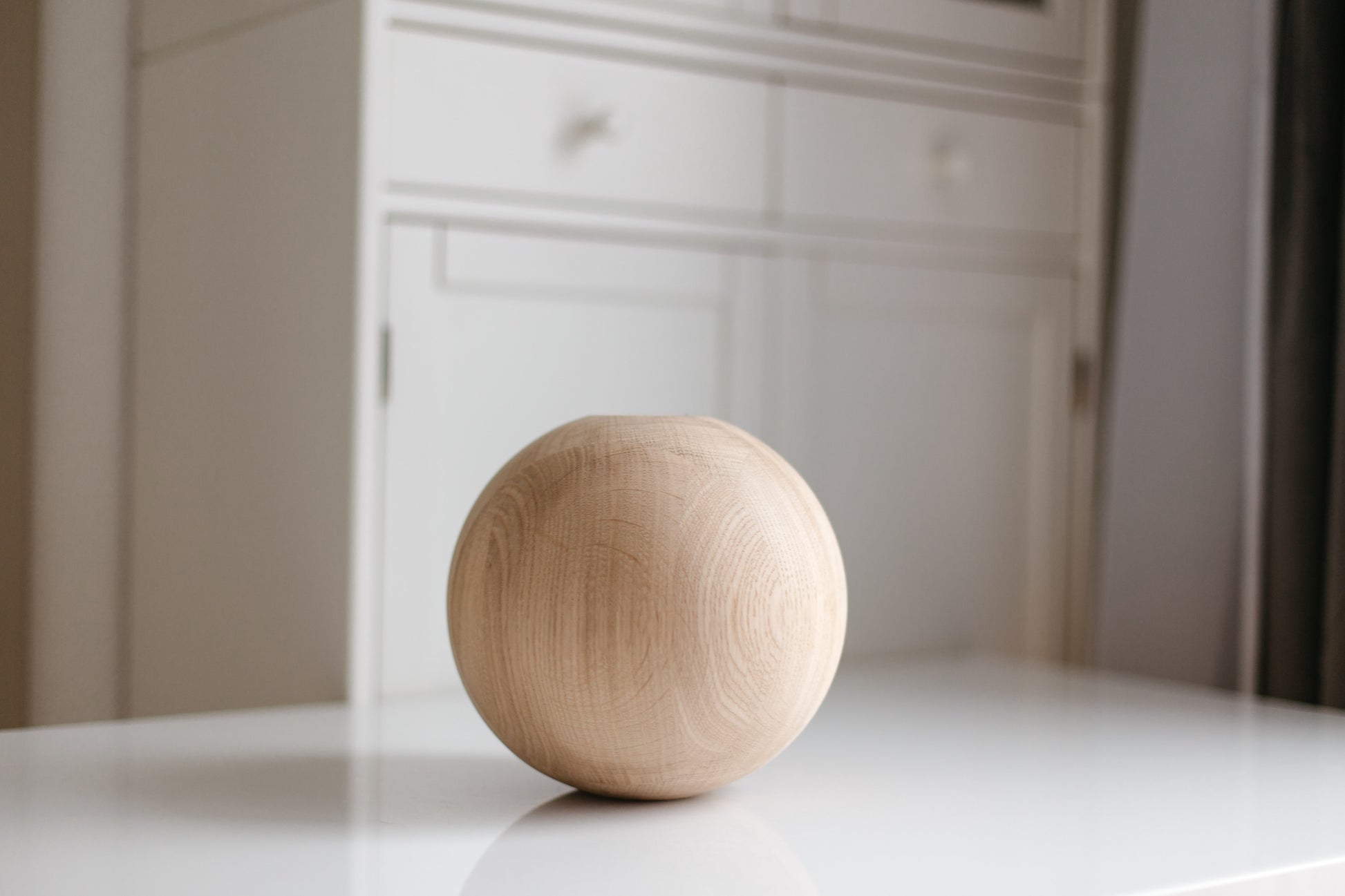 Wooden sphere on a white surface with a blurred background