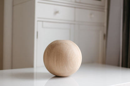 Wooden sphere on a white surface with a blurred background