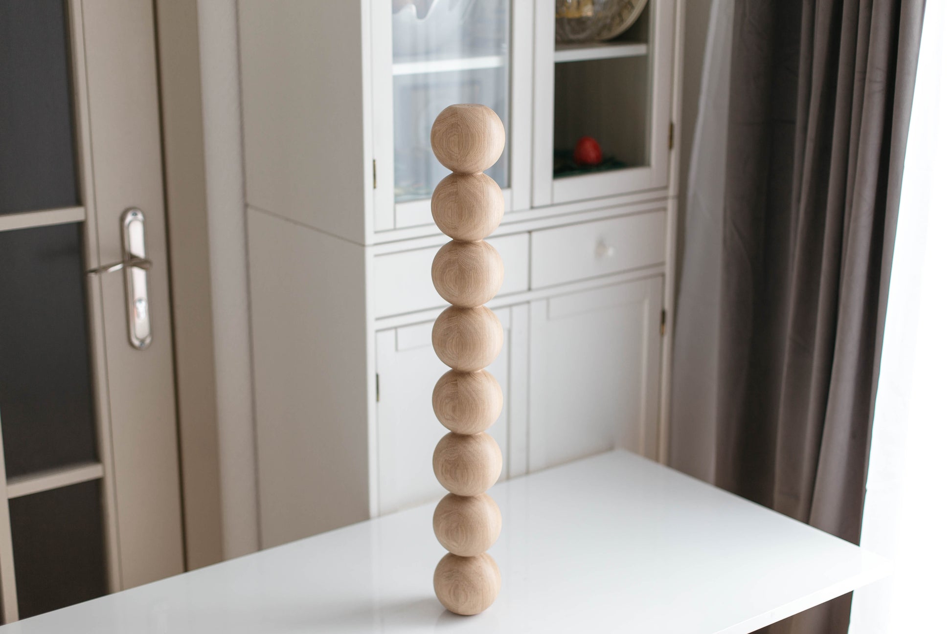 Wooden sculpture on a white surface with a neutral background