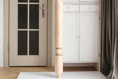 Wooden bedpost in a room with a door and wardrobe.