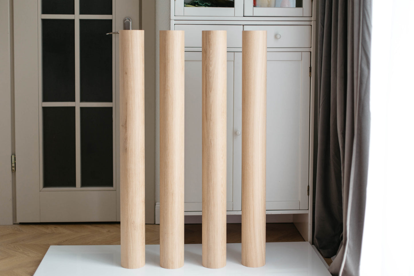 Three wooden legs on a white surface with a neutral background