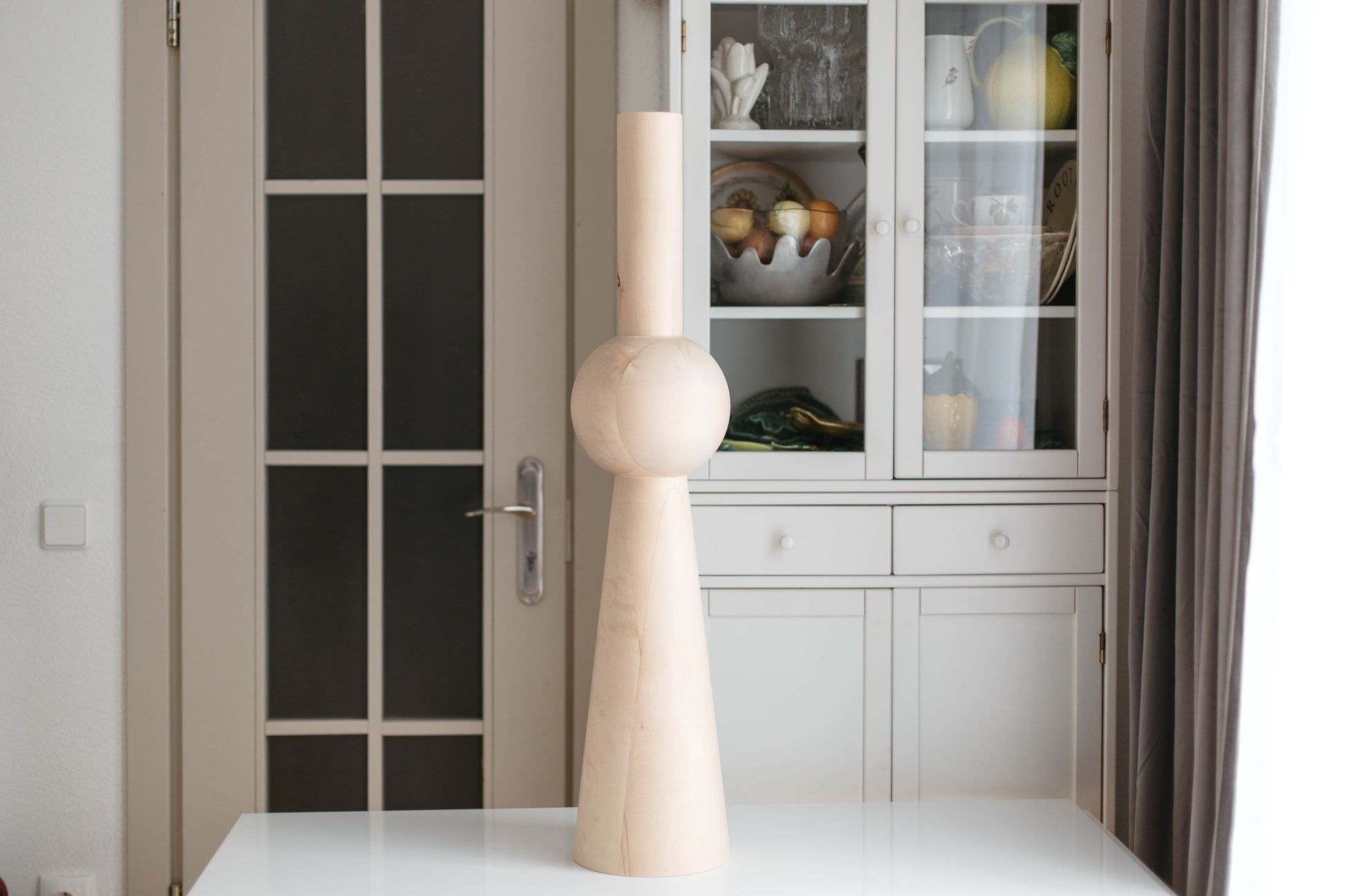 Decorative vase on a table with a glass cabinet in the background