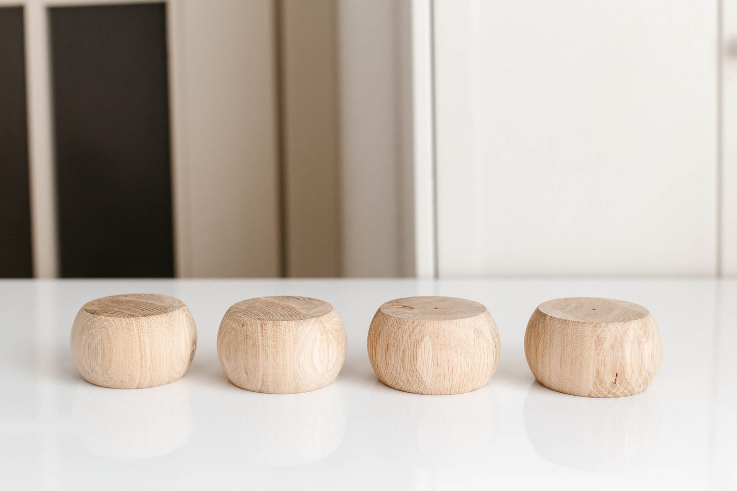 Four wooden cylindrical objects on a white surface with a neutral background