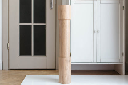 Wooden cylindrical object on a white rug in a room with a door and cabinet.