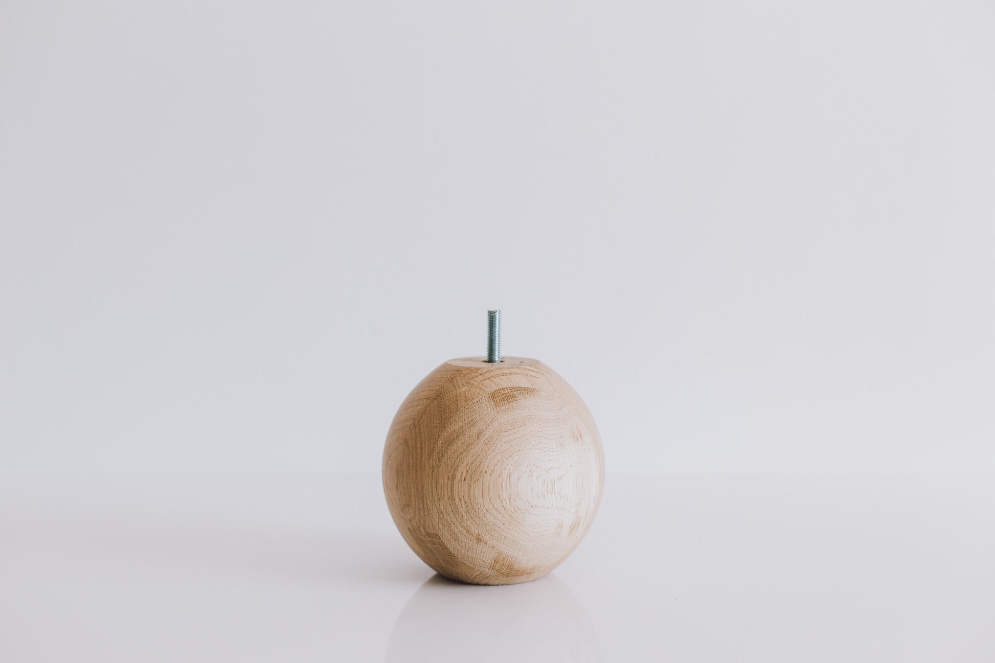 A single round turned wooden leg with a sphere shape, displayed against a white background.