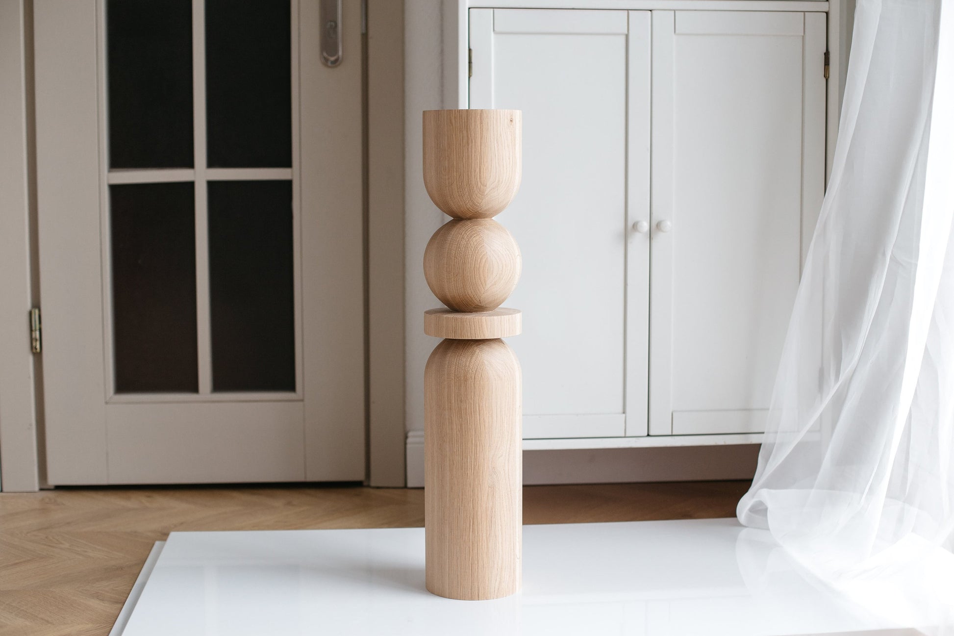 A single wooden furniture leg standing upright on a white surface, with a plain and smooth finish.
